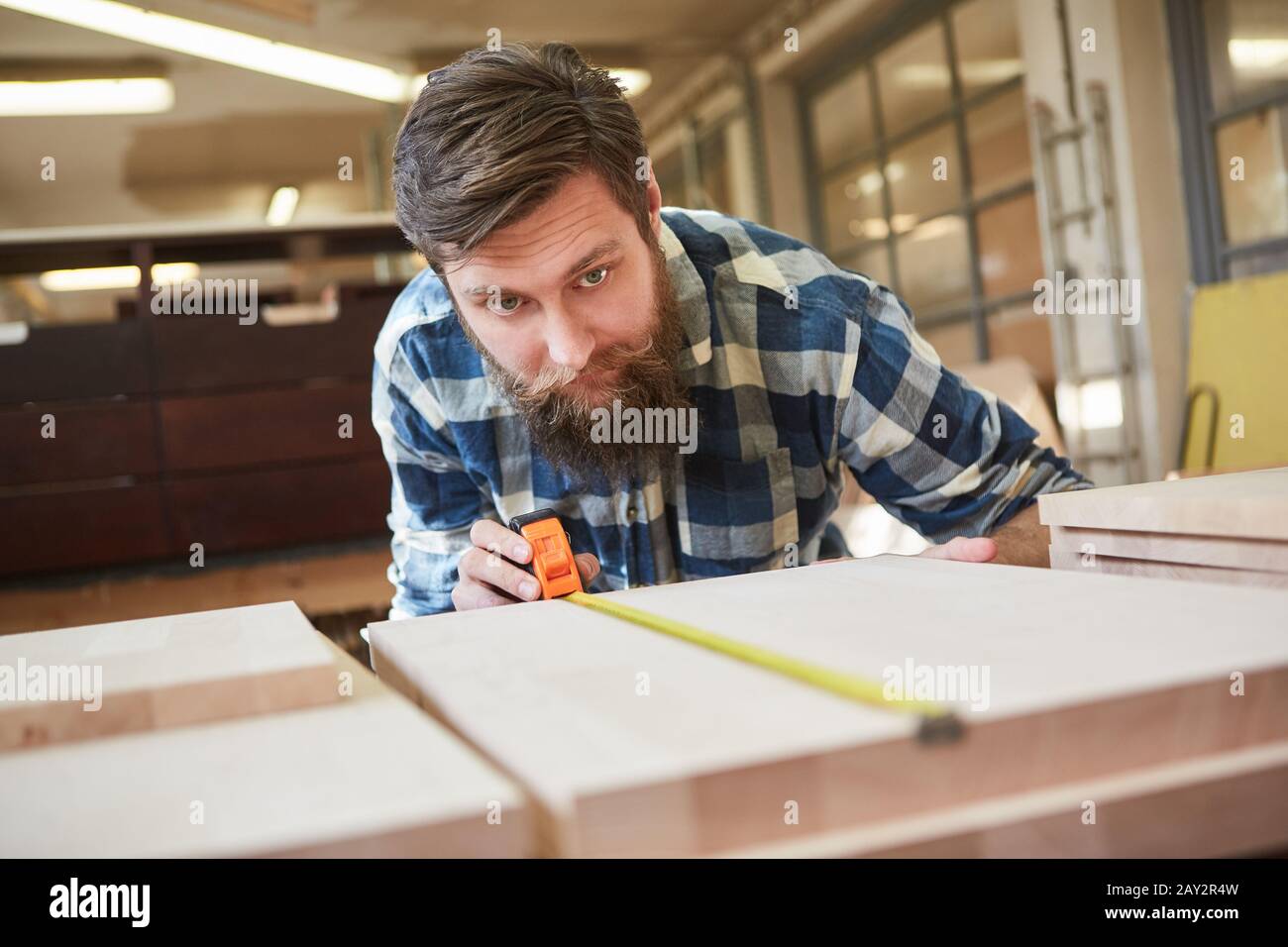 Carpenter apprentice with ruler measuring wood in carpentry Stock Photo