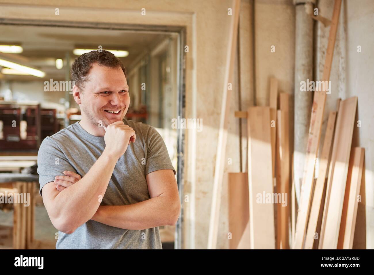 Young man as a satisfied carpenter apprentice in the carpentry workshop Stock Photo