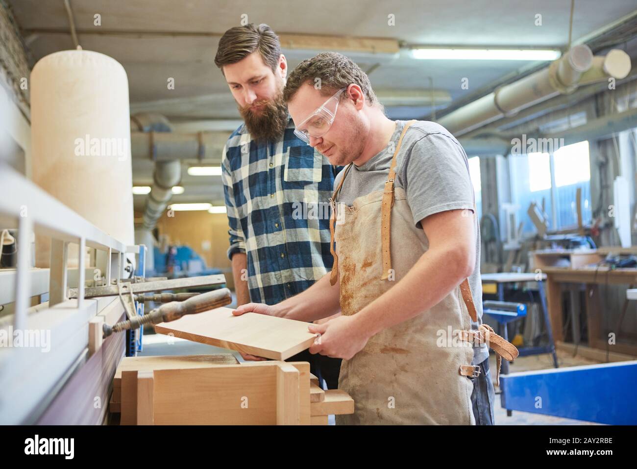 The team of furniture makers controls the quality of wood on a workpiece in the joinery Stock Photo