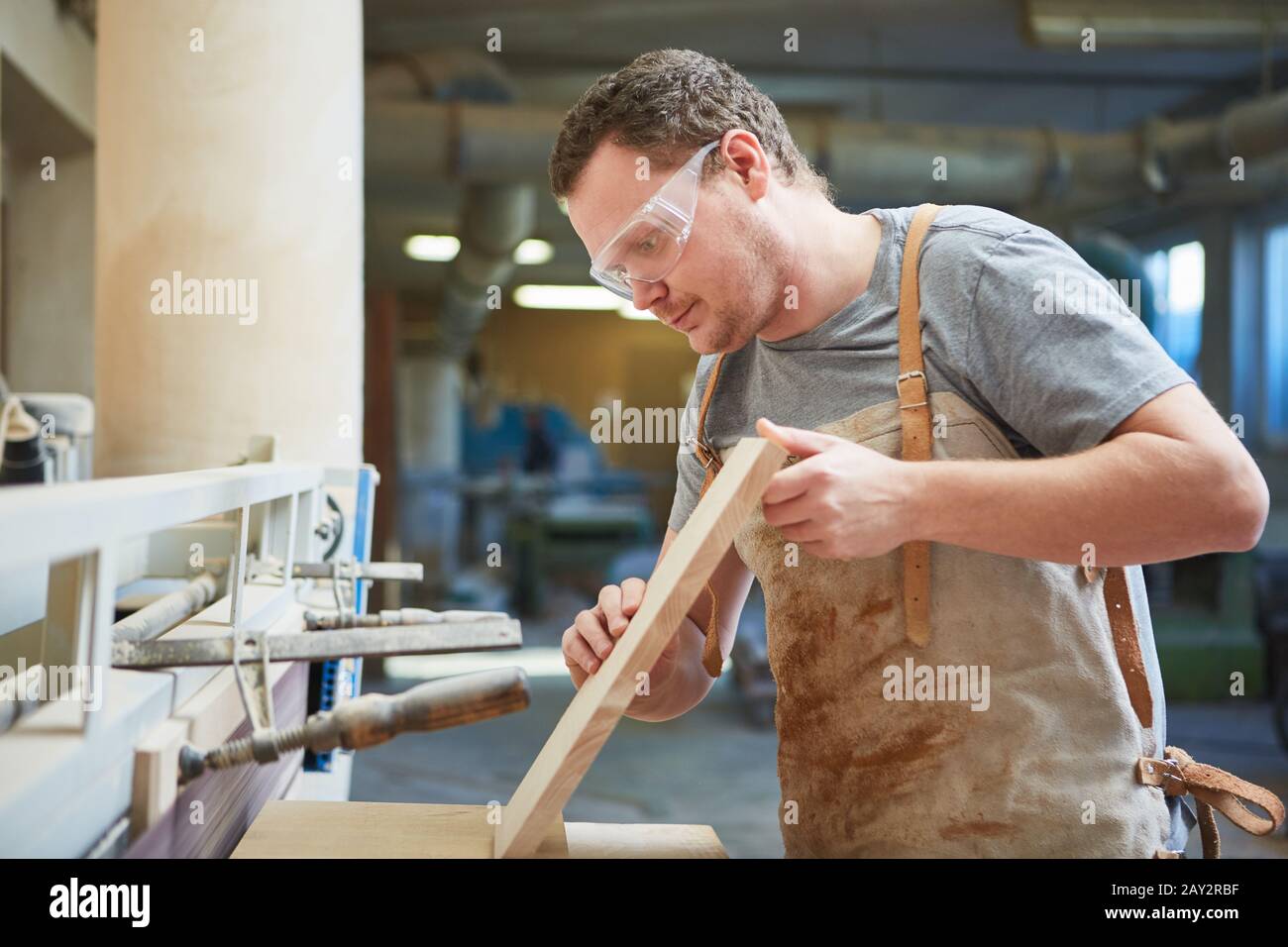 Furniture maker as an apprentice works on the grinding machine in the carpentry Stock Photo