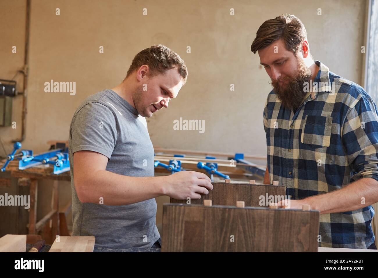 Apprentice in training in a joinery helps build furniture out of wood Stock Photo