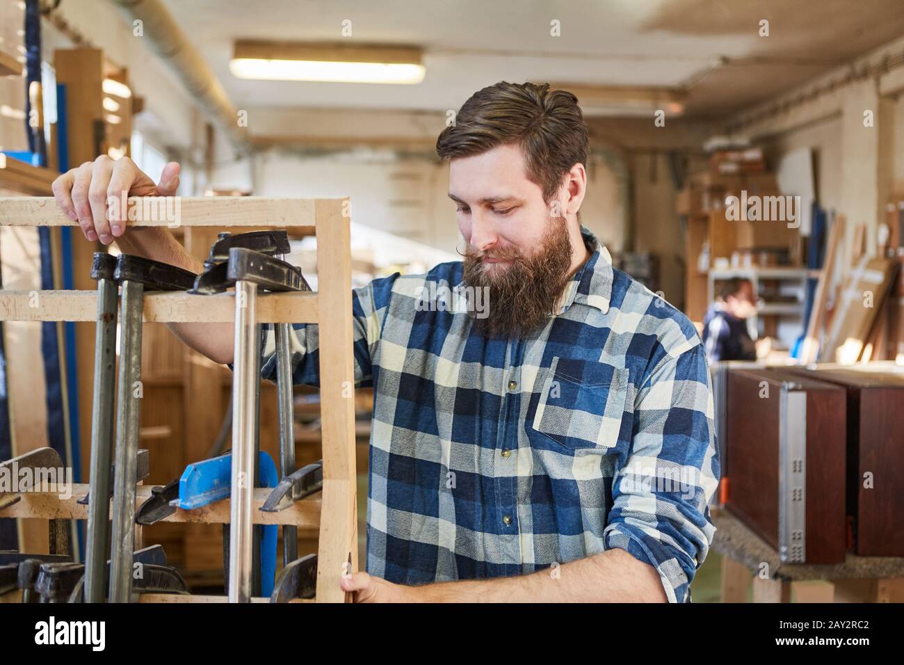 Man as a Carpenter with screw clamps in a joinery Stock Photo