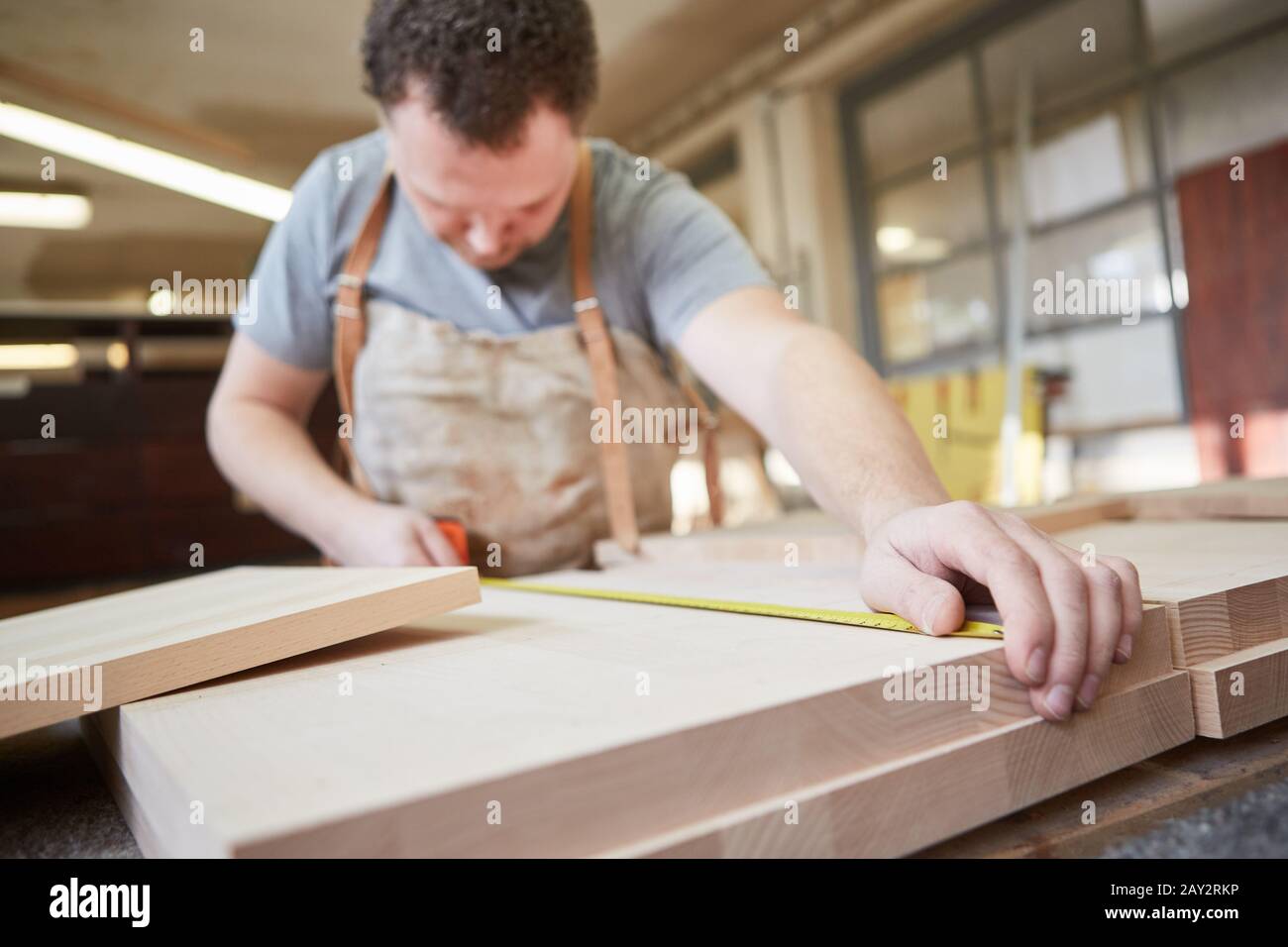 Furniture maker with tape measure while measuring from a shelf in the carpentry Stock Photo