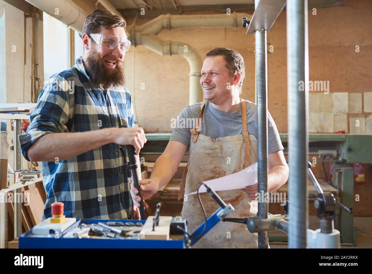 Two cheerful carpenters as a team in the joinery discuss an order Stock Photo