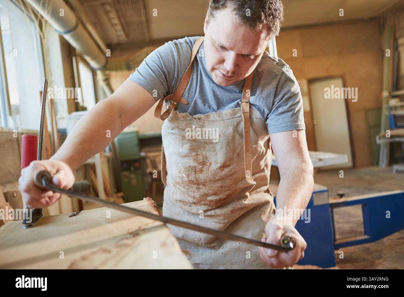 A carpenter apprentice debarking wood with a pull knife or peeling iron Stock Photo