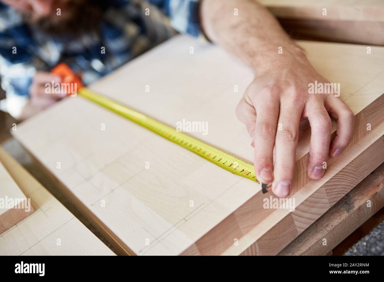 Carpenter as a furniture maker with a tape measure when measuring wood for a shelf Stock Photo