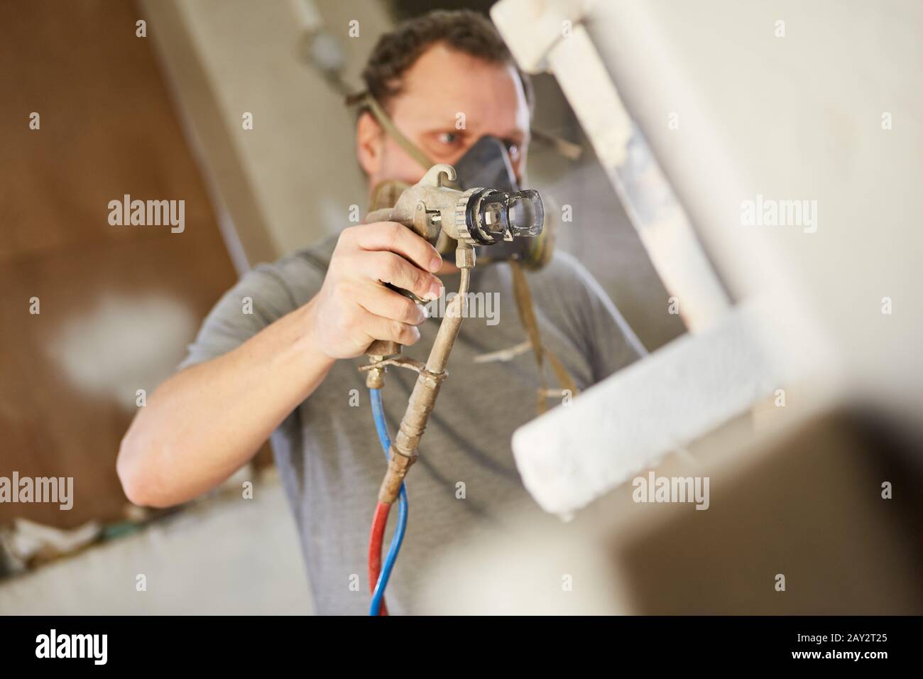 Painter with and respiratory protection and spray gun stain or paint the wood Stock Photo