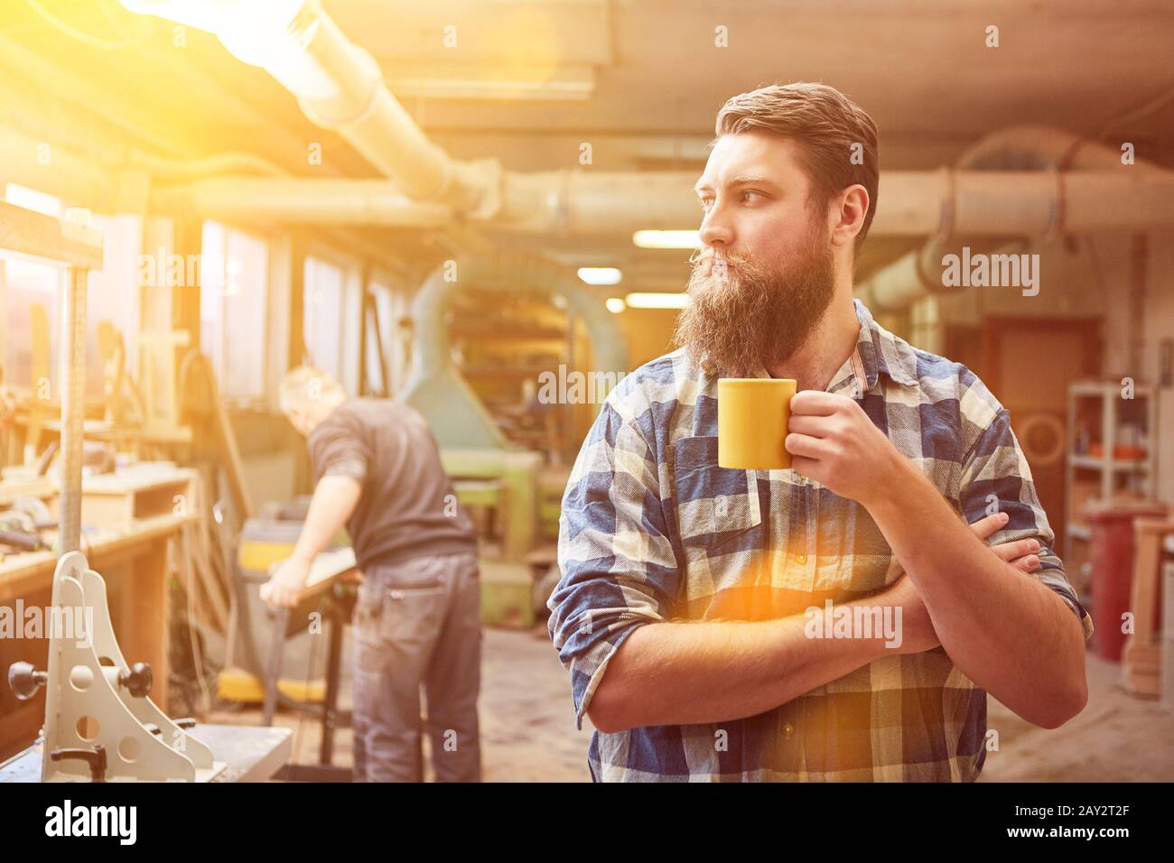 Self-employed hipster carpenter drinking coffee in the workshop Stock Photo