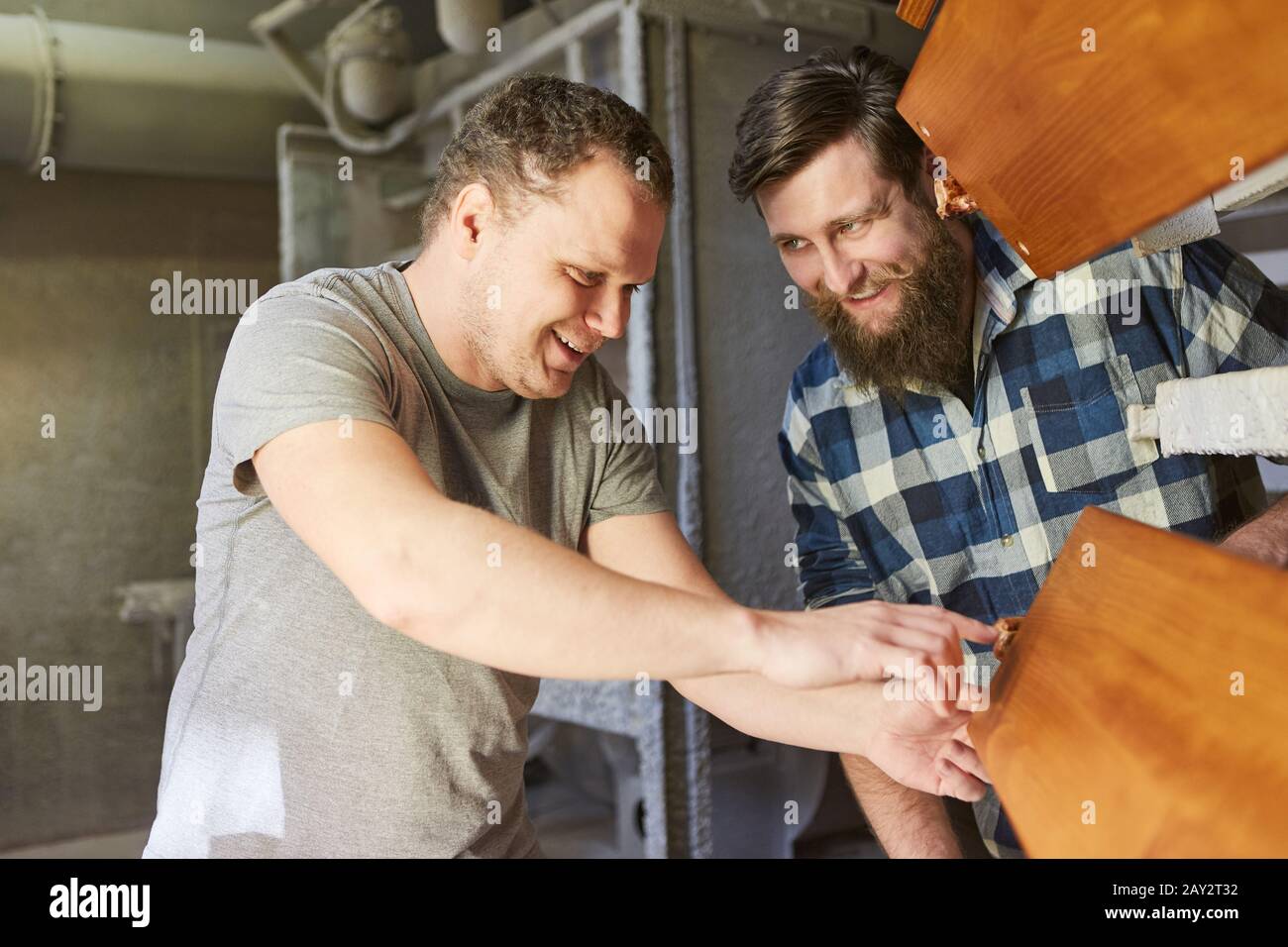 Carpenter instructor and apprentice look at a wood board in the carpentry shop Stock Photo