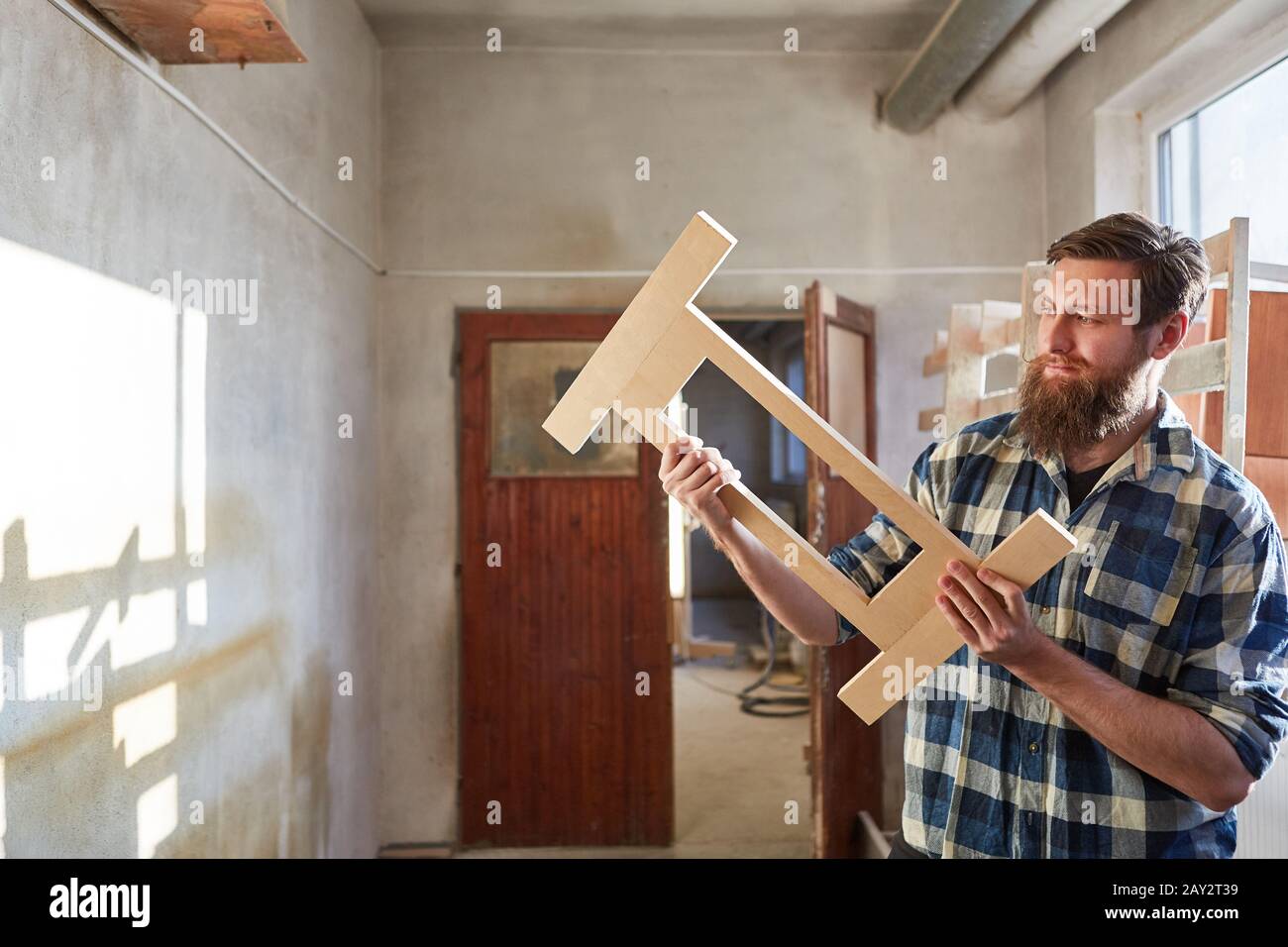 Carpenter training to be a furniture maker checks a workpiece Stock Photo