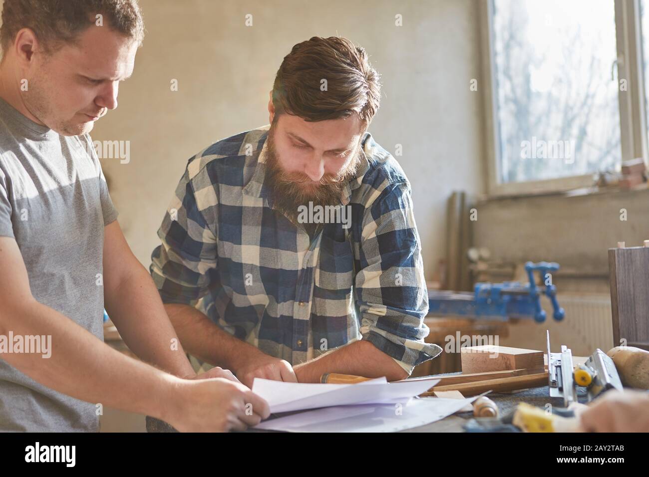 Two carpenters with order on a sheet of paper in the carpentry shop Stock Photo