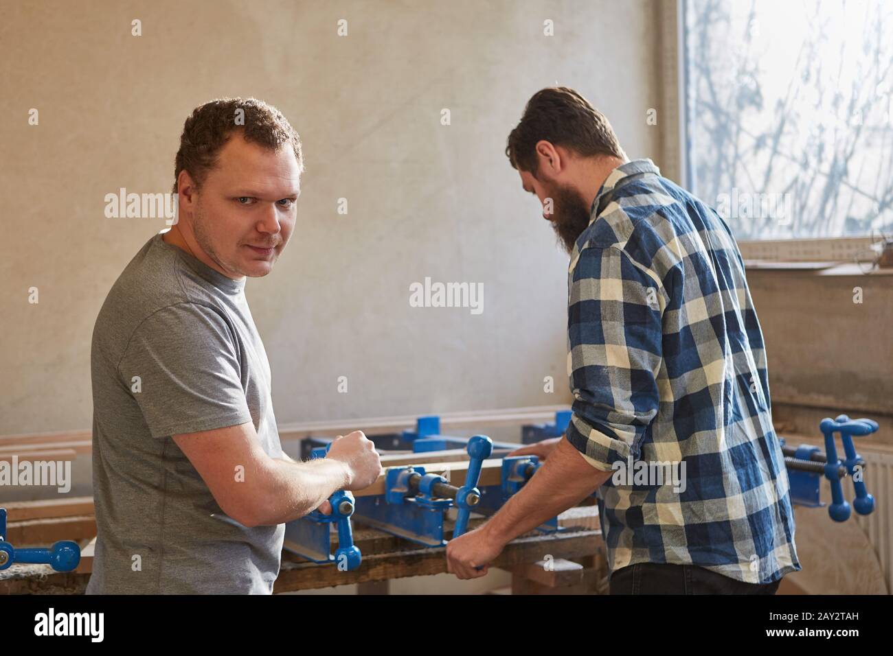 Carpenters work together as furniture makers on vices in the carpentry workshop Stock Photo