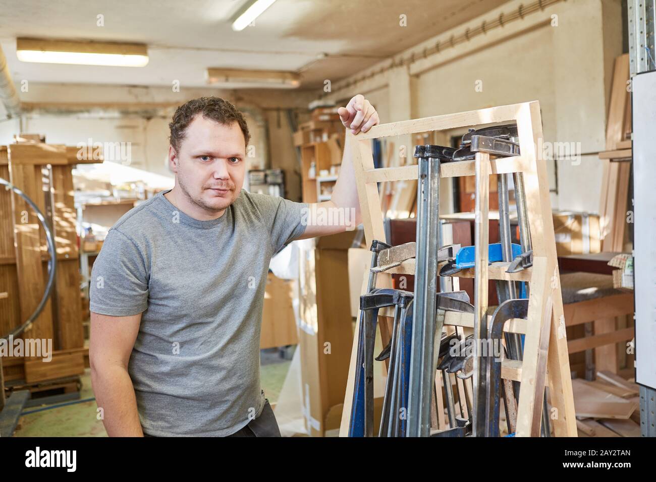 Young craftsman as a Carpenter with a selection of clamps Stock Photo