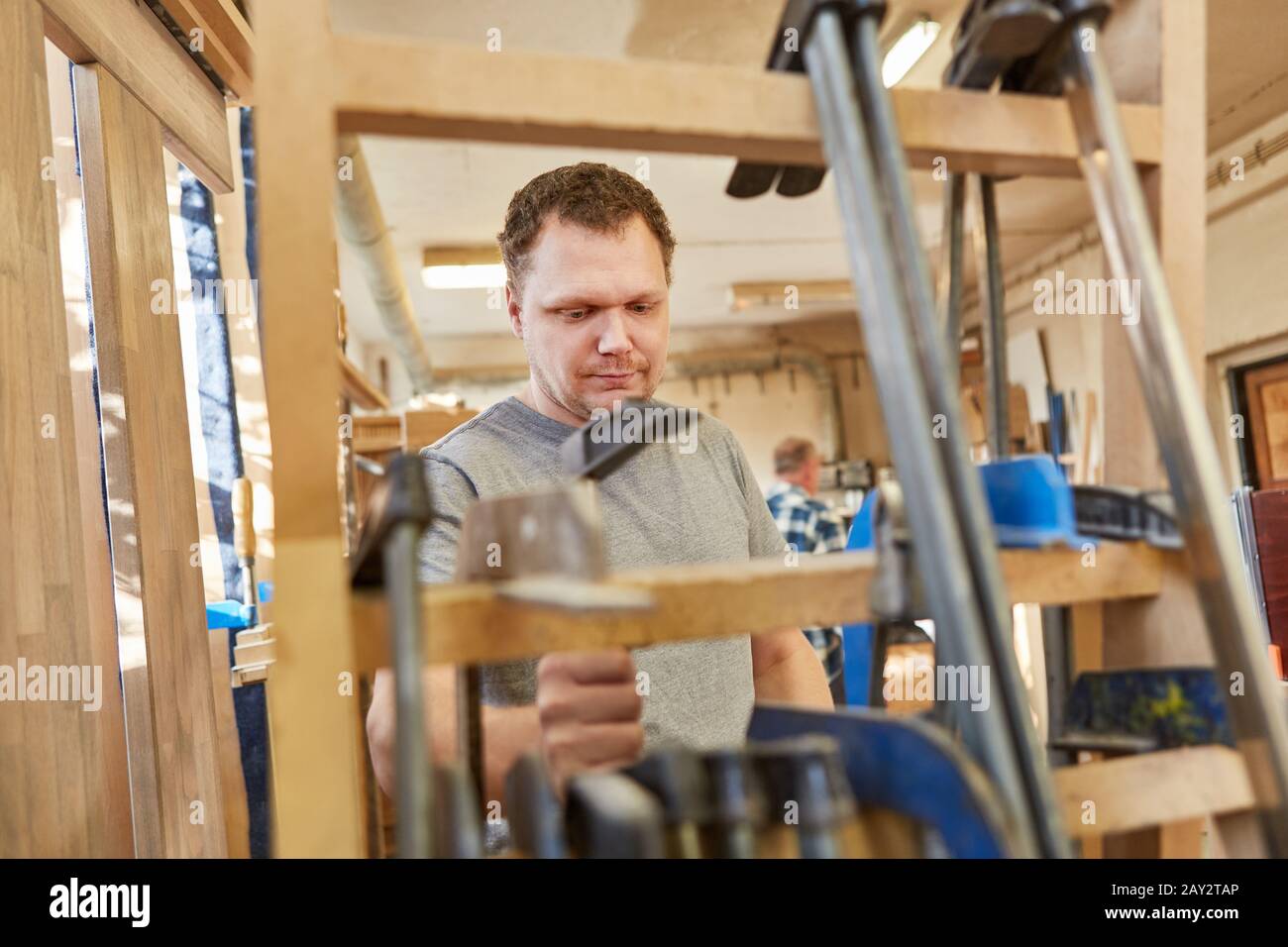 Young Carpenter works with clamps in the joinery Stock Photo