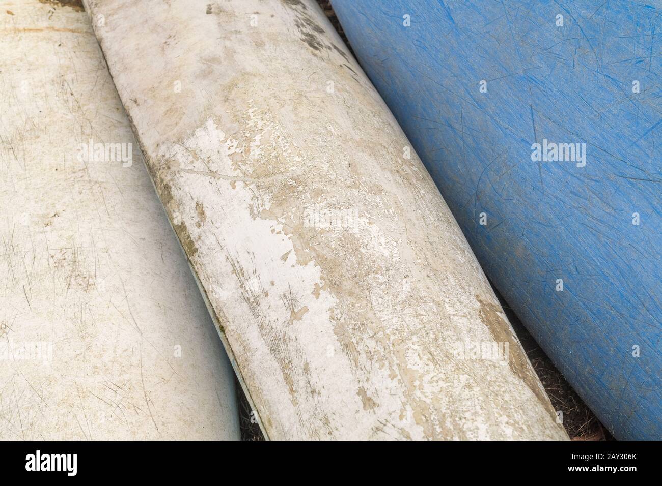 Three upturned fibreglass hulls of beached kayaks, showing glass fibre strands and glass fabric structure and texture. Stock Photo