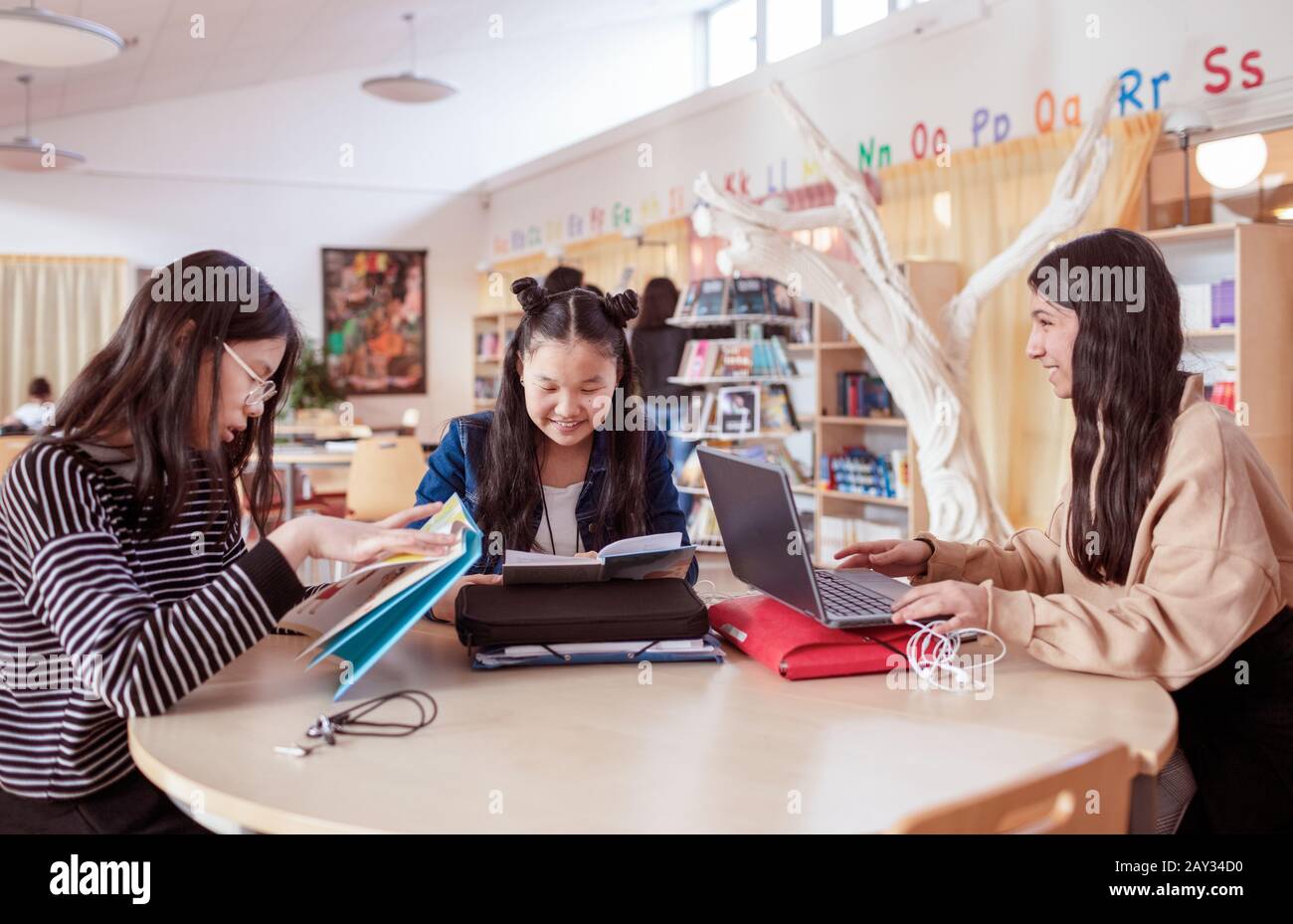 Teenage girls sitting together in library Stock Photo - Alamy