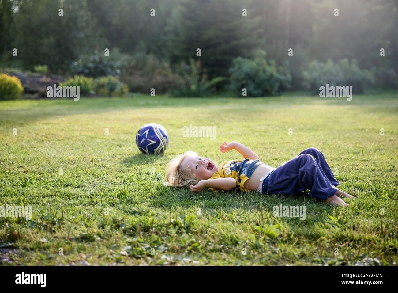 Happy boy lying on lawn Stock Photo