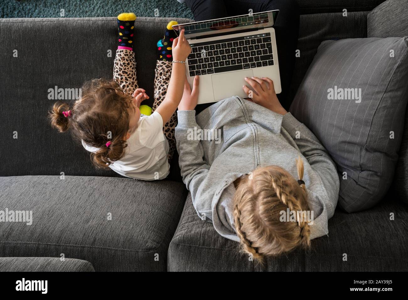 Sisters on sofa using laptop Stock Photo - Alamy