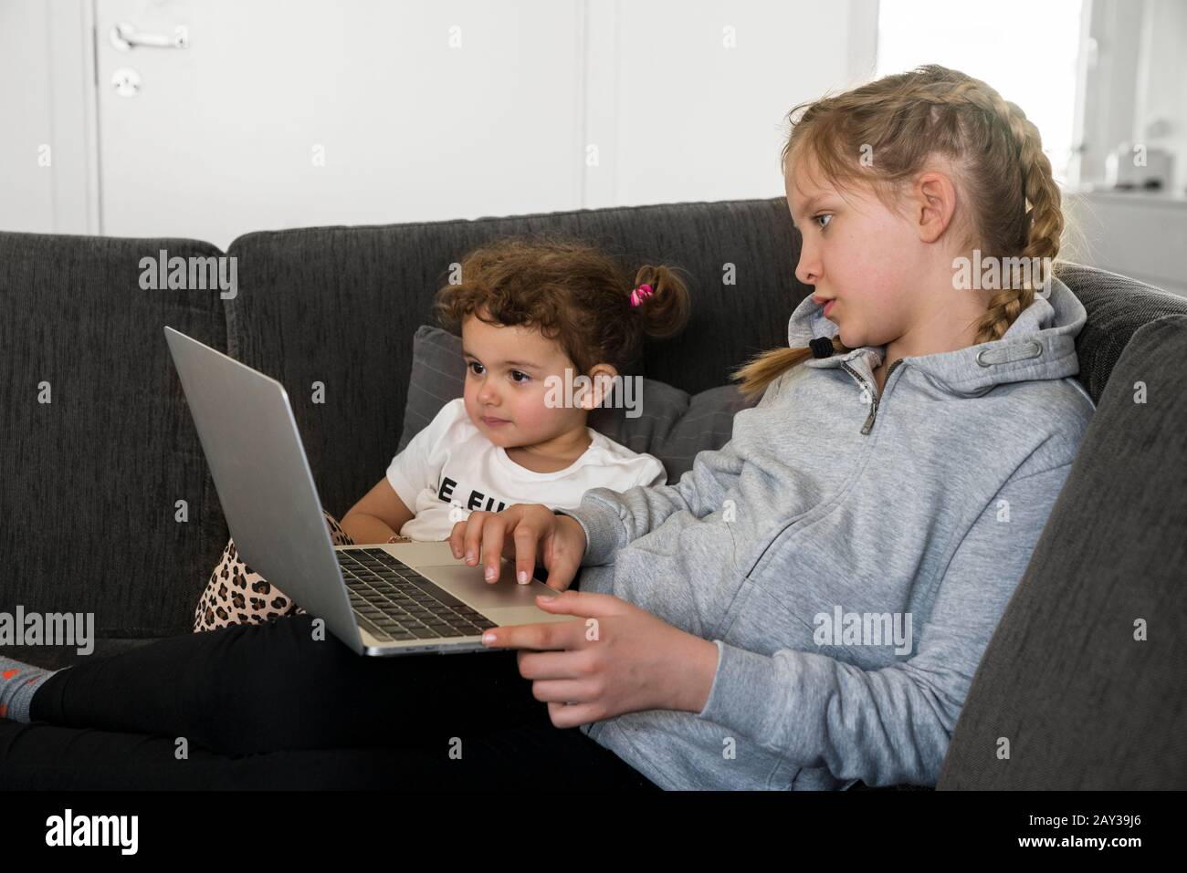 Sisters on sofa using laptop Stock Photo - Alamy