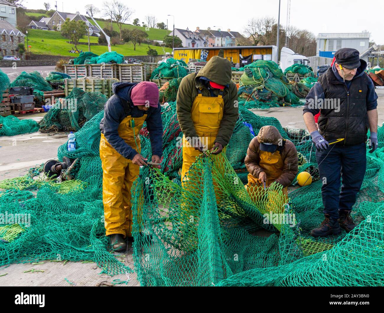 4 fishermen mending nets in union hall harbour ireland Stock Photo
