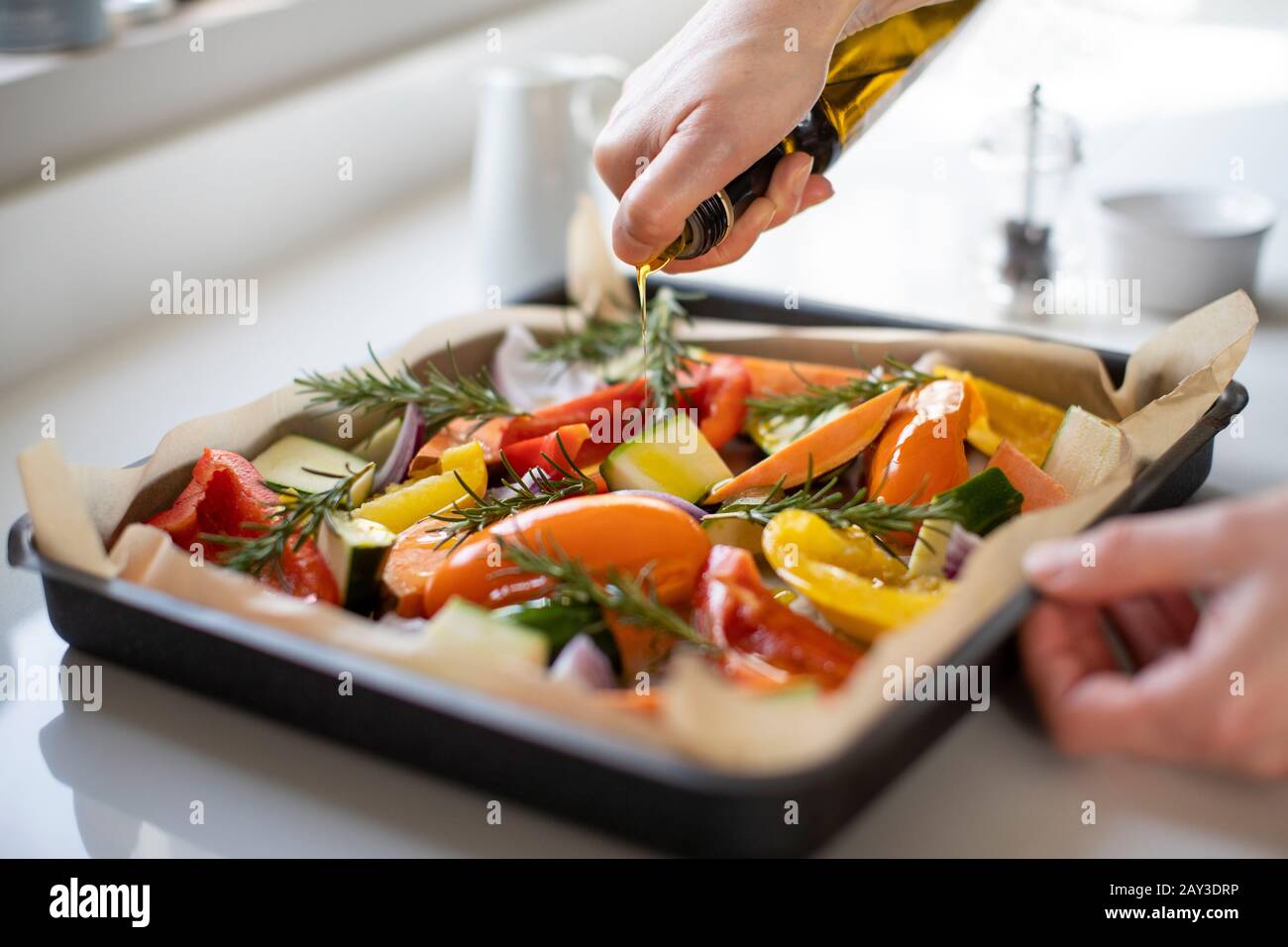 Close Up Of Seasoning Tray Of Vegetables For Roasting With Olive Oil Ready For Vegan Meal Stock Photo