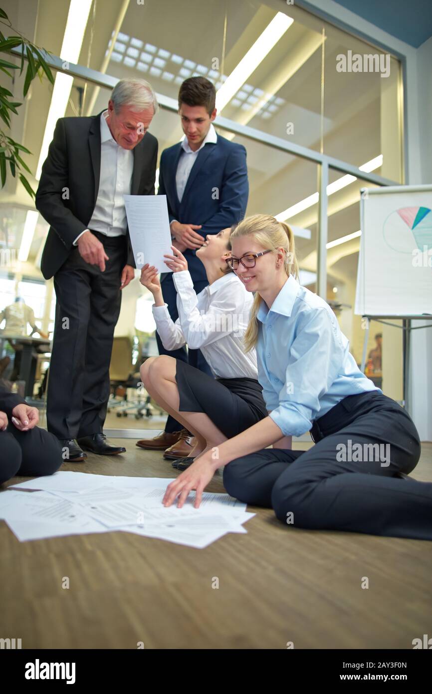 Business people in startup company sort papers on the floor Stock Photo