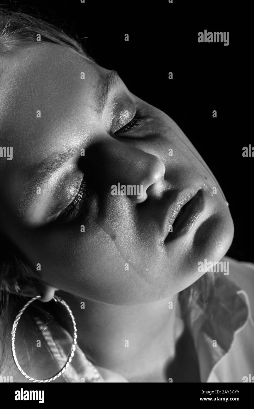 sad woman with closed eyes crying, on black background, closeup portrait, monochrome Stock Photo