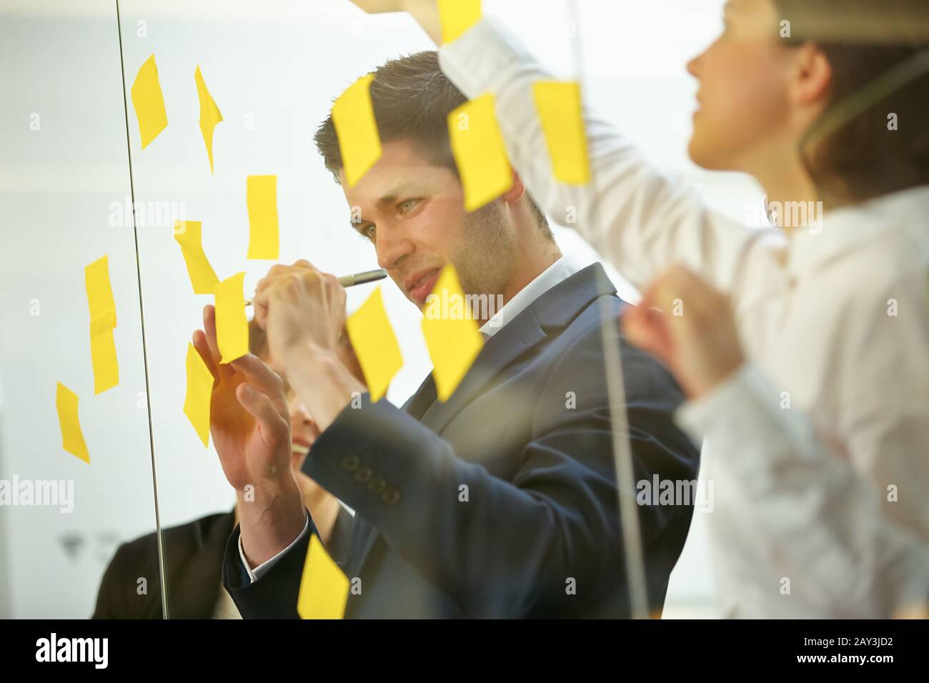 Business team writes notes while brainstorming on a glass wall Stock Photo