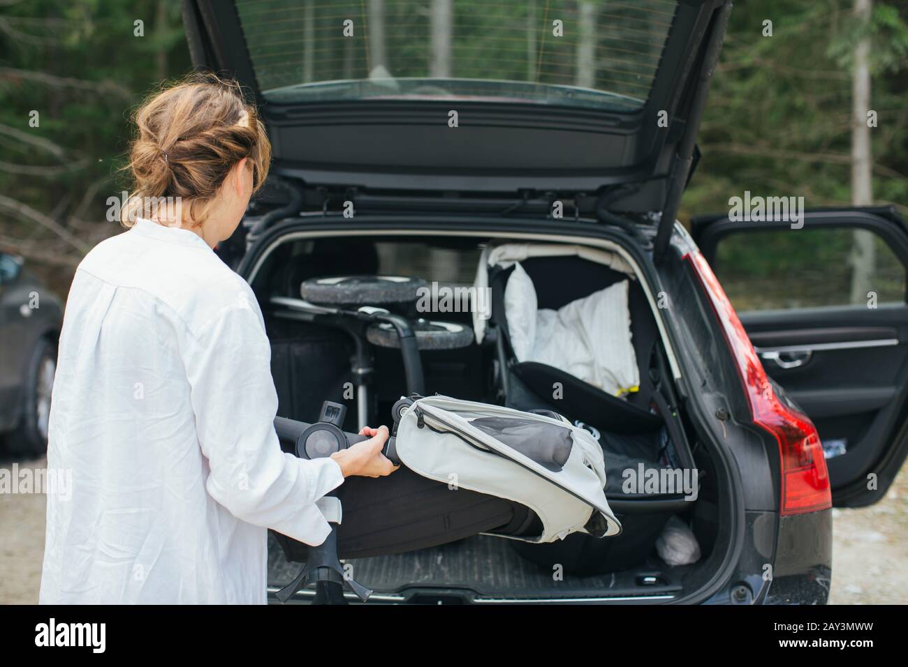 Woman loading pram into car boot Stock Photo