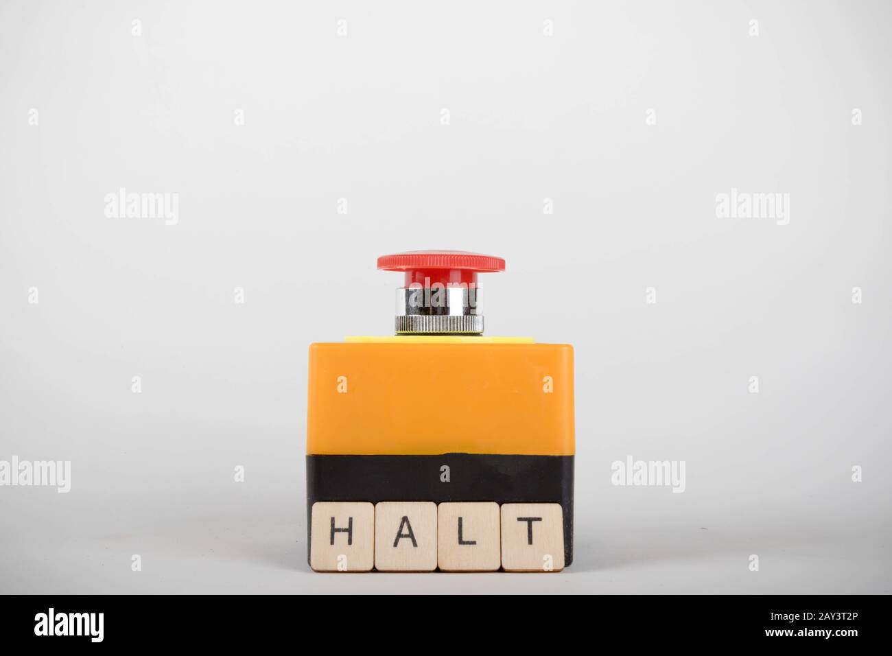 An industrial emergency stop button with a sign reading Halt Stock Photo