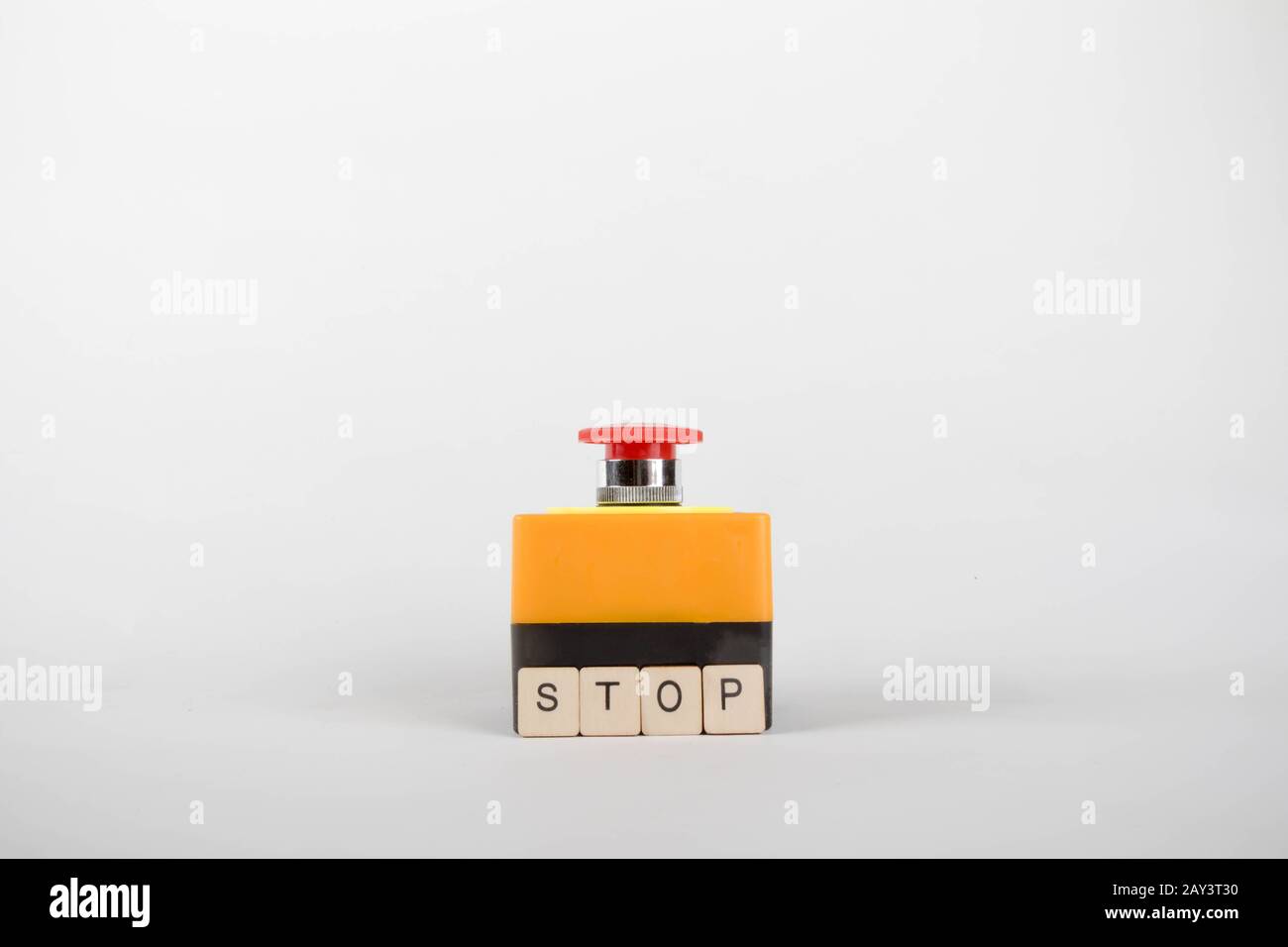 An industrial emergency stop button with a sign reading Stop Stock Photo