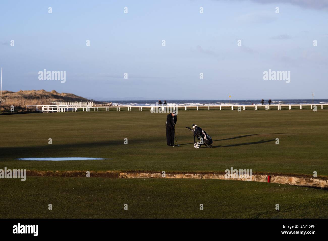 ST ANDREWS, SCOTLAND - 13/2/2020 - A golfer sets up to take a shot on the 18th hole of the old course between the swilcan burn and west sands Stock Photo