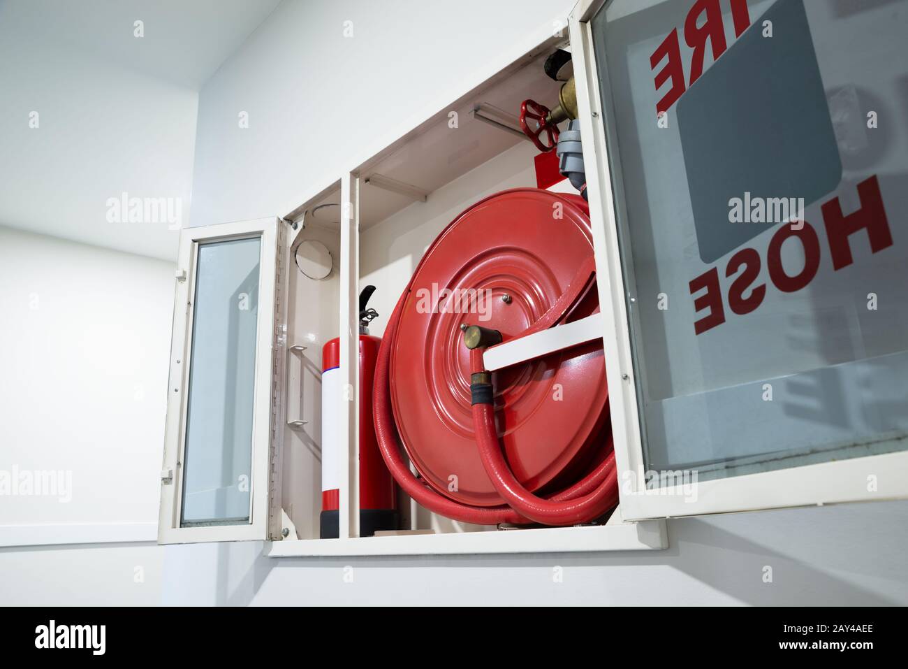 Fire extinguisher and fire hose reel hanging on the wall in building,  safety concept Stock Photo - Alamy
