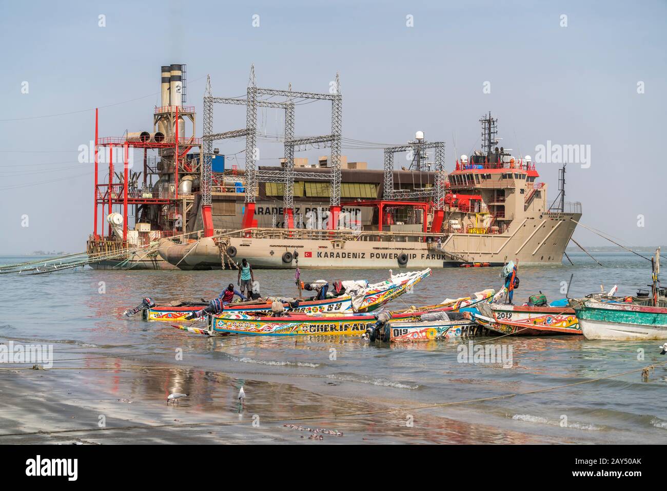 Das schwimmende Kraftwerk Karadeniz Powership Faruk Bey und Fischerboote an der Küste bei Banjul, Gambia, Westafrika  |  Karadeniz Powership Faruk Bey Stock Photo