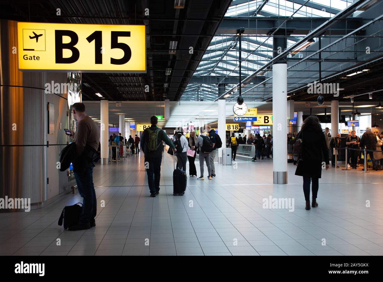 Airport terminal gate with gate number for departing flights, passengers waiting with luggage and suitcase Stock Photo