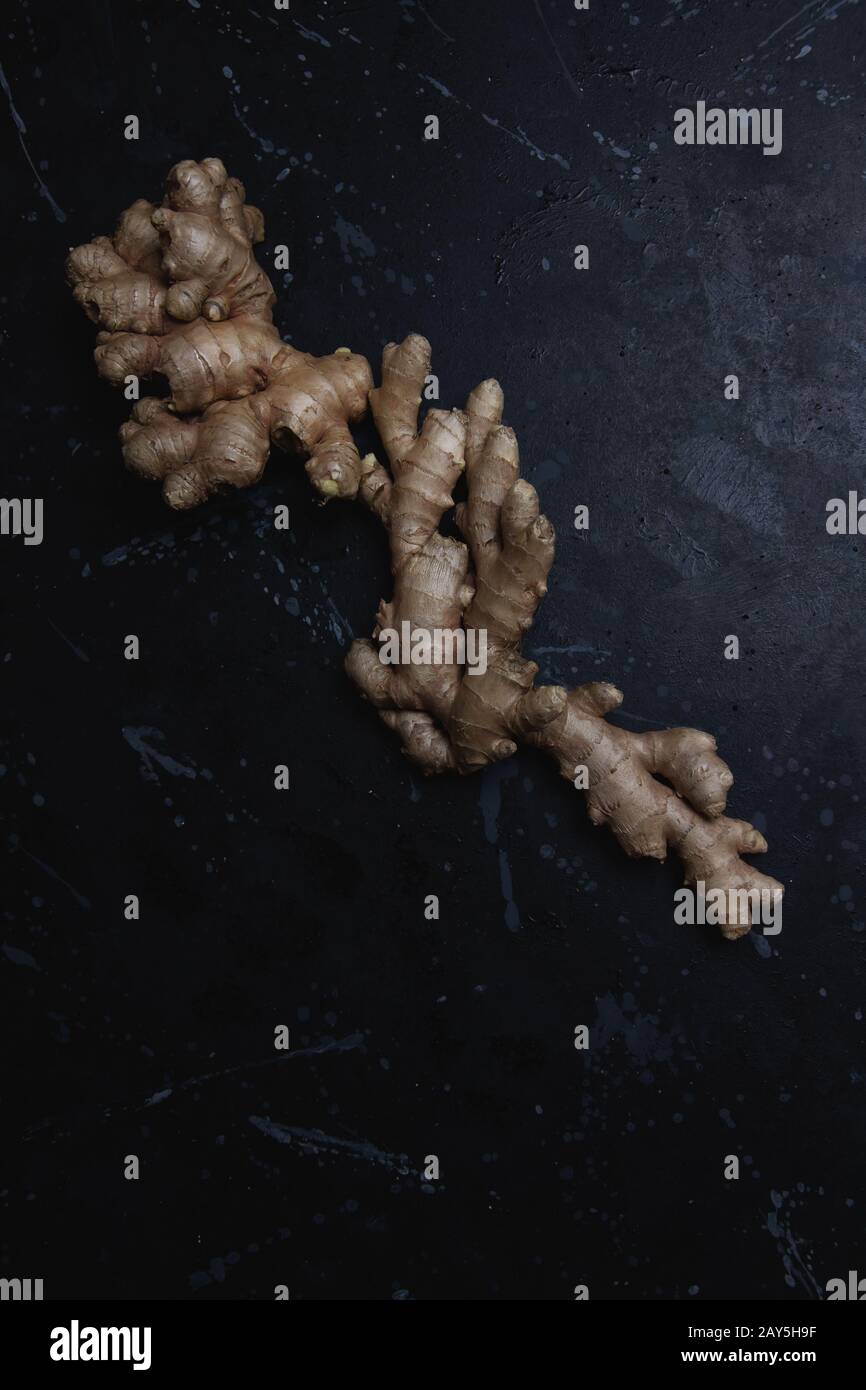Big fresh ginger root on a black distressed background, Flat lay, dark food Stock Photo