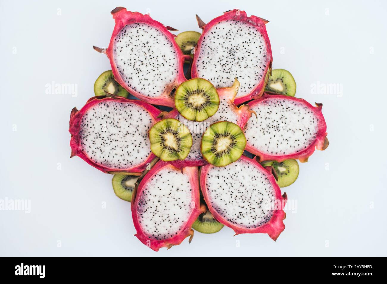 Food art concept. Sliced green kiwi and dragon fruit formed in form of flower. Fresh healthy exotic fruit on white background. Healthy eating and vita Stock Photo