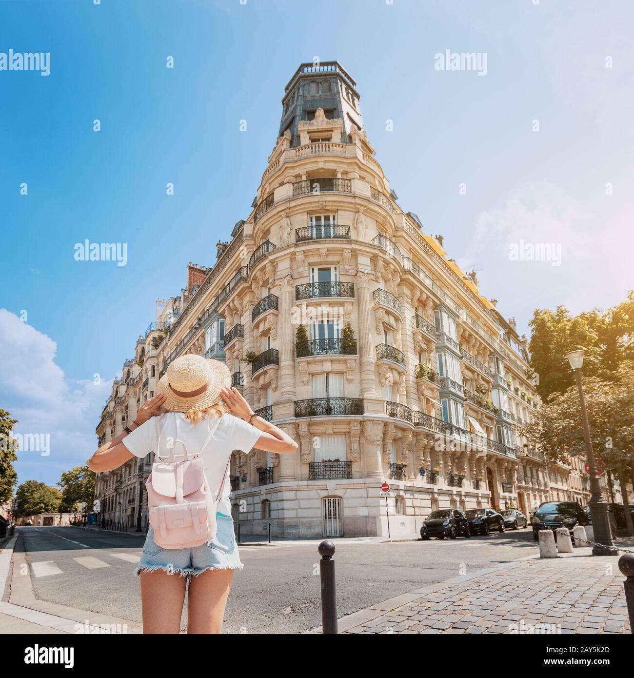 A woman stands near a typical Parisian residential corner house. Concept of apartments or hotels for tourists Stock Photo