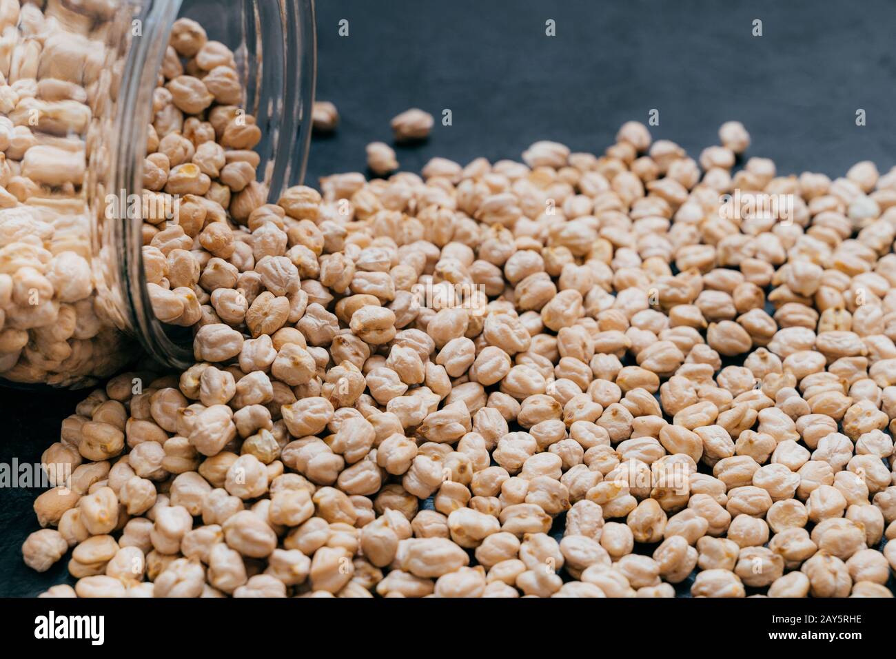 Glass jar with raw garbanzo. Chickpea grains isolated on dark