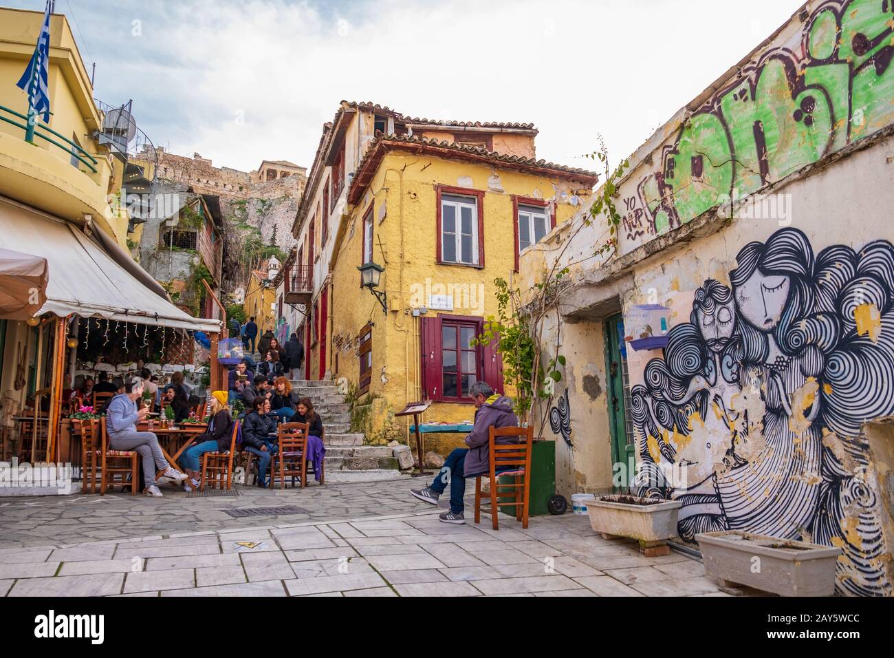 Athens, Greece - January 25, 2020: People relax in a cafe in Plaka area of Athens with the Acropolis in the background Stock Photo