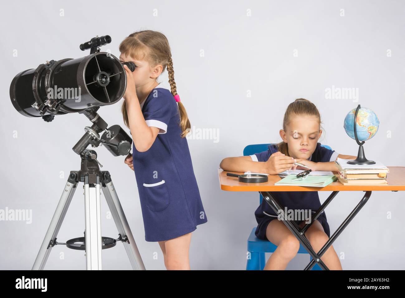 Girl watching the celestial bodies in the telescope, the other girl is waiting for the results of observations Stock Photo