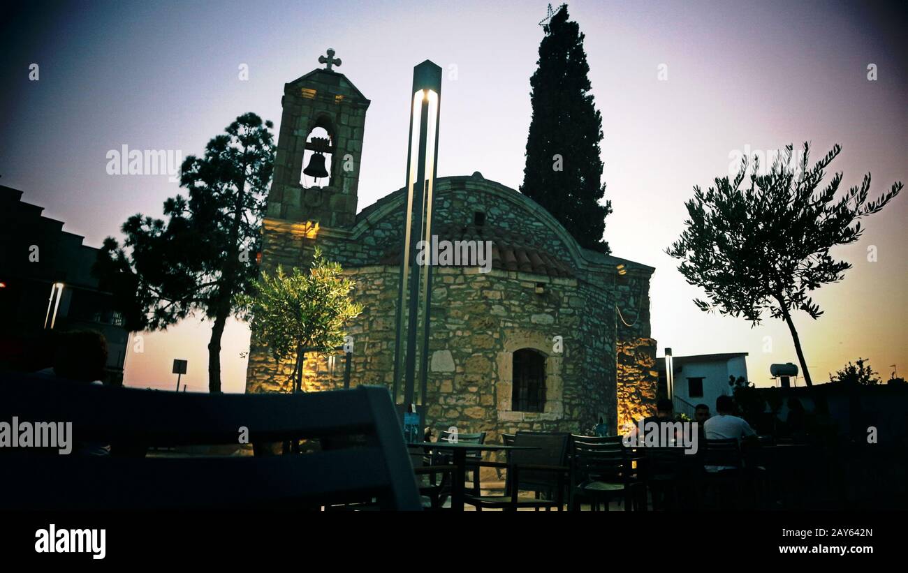 Old stone church steeple with bell and cross silhouetted at dusk Stock Photo