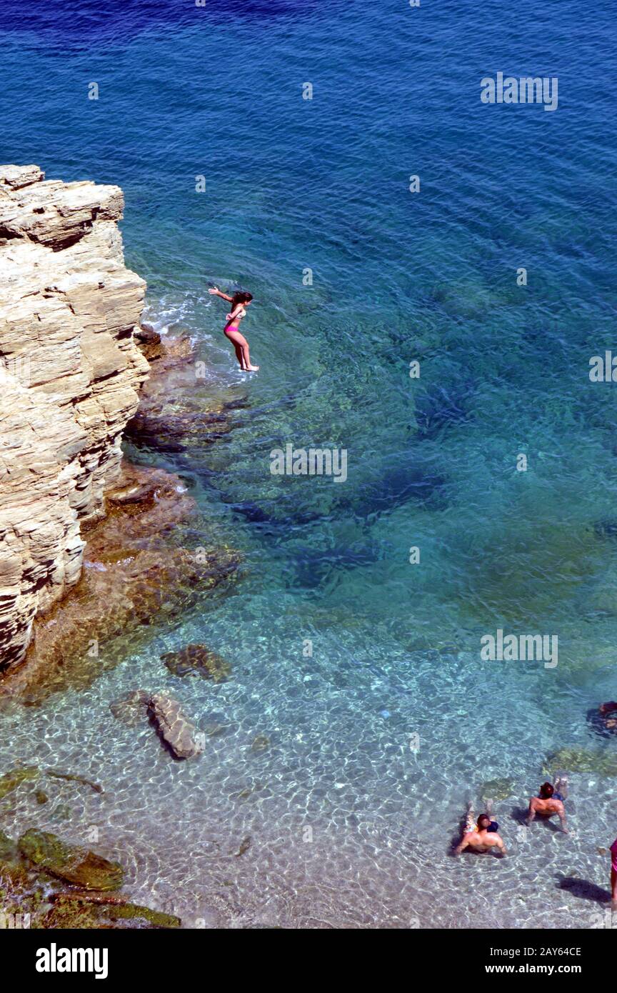 Girl who jumps since a cliff into the transparent sea Stock Photo - Alamy