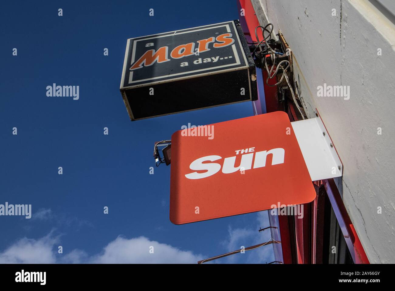 British tabloid newspaper The Sun and ' A Mars a day' sign sit on the exterior wall of a newsagent in Southeast London, London, UK Stock Photo