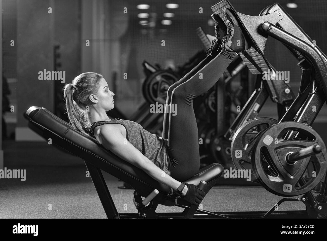 Sportive woman using weights press machine for legs. Gym. Stock Photo