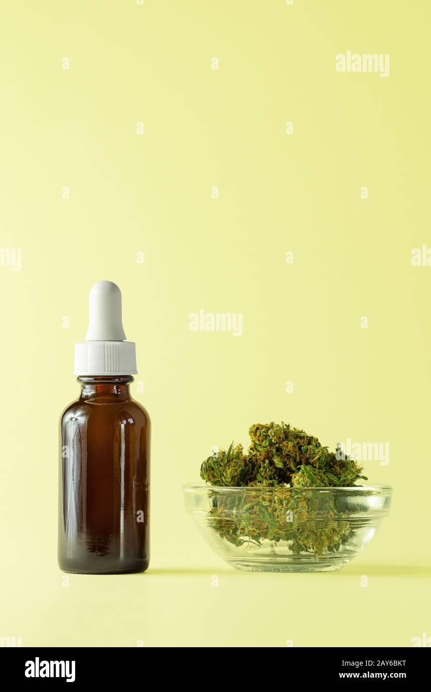 Glass Bottle of CBD or THC Oil with Hemp or Cannabis Buds Isolated on Yellow Background with Copy Space Stock Photo