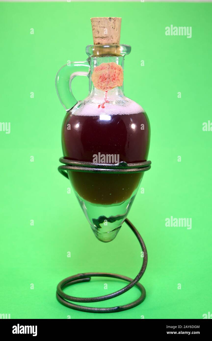 Glass amphora on green bottom with some red vinegar rest on a tripod in the shape of spring. Stock Photo