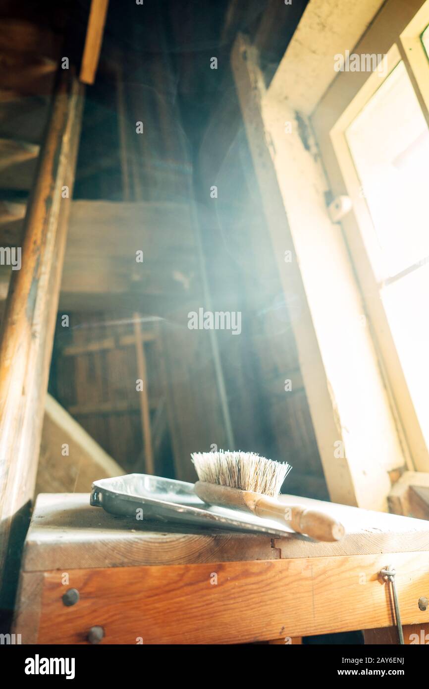 A wooden brush with natural bristles and a metal scoop lying on a wooden surface Stock Photo