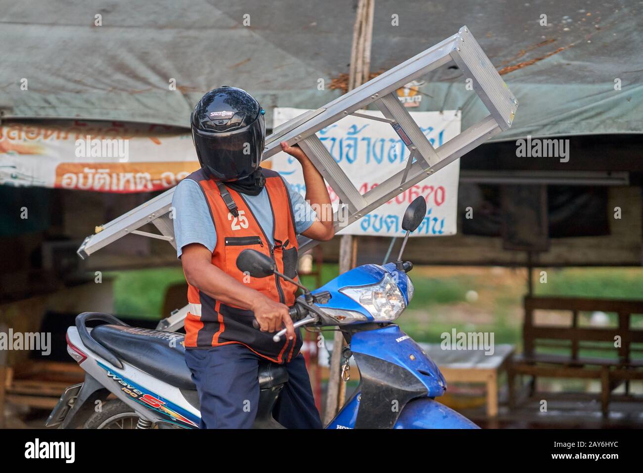 A taxi motorcyclist carrying a ladder. Stock Photo