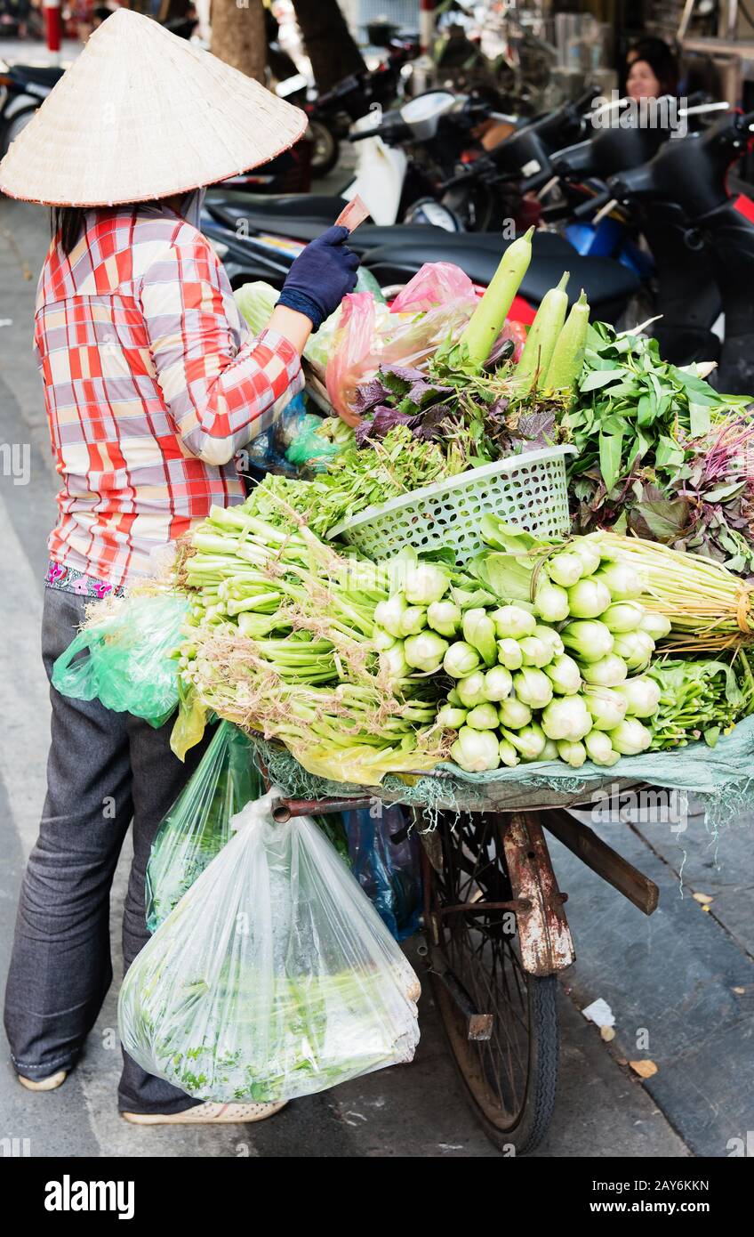 Vietnamese woman carrying baskets of fruit and vegetables on the street in Hue, Vietnam Stock Photo
